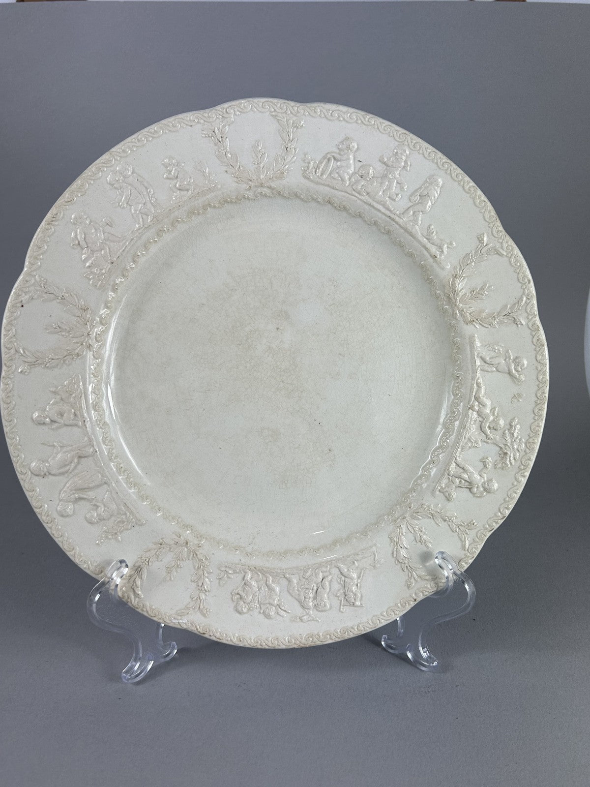 Early Wedgwood creamware plate with moulded putti border, 26cm