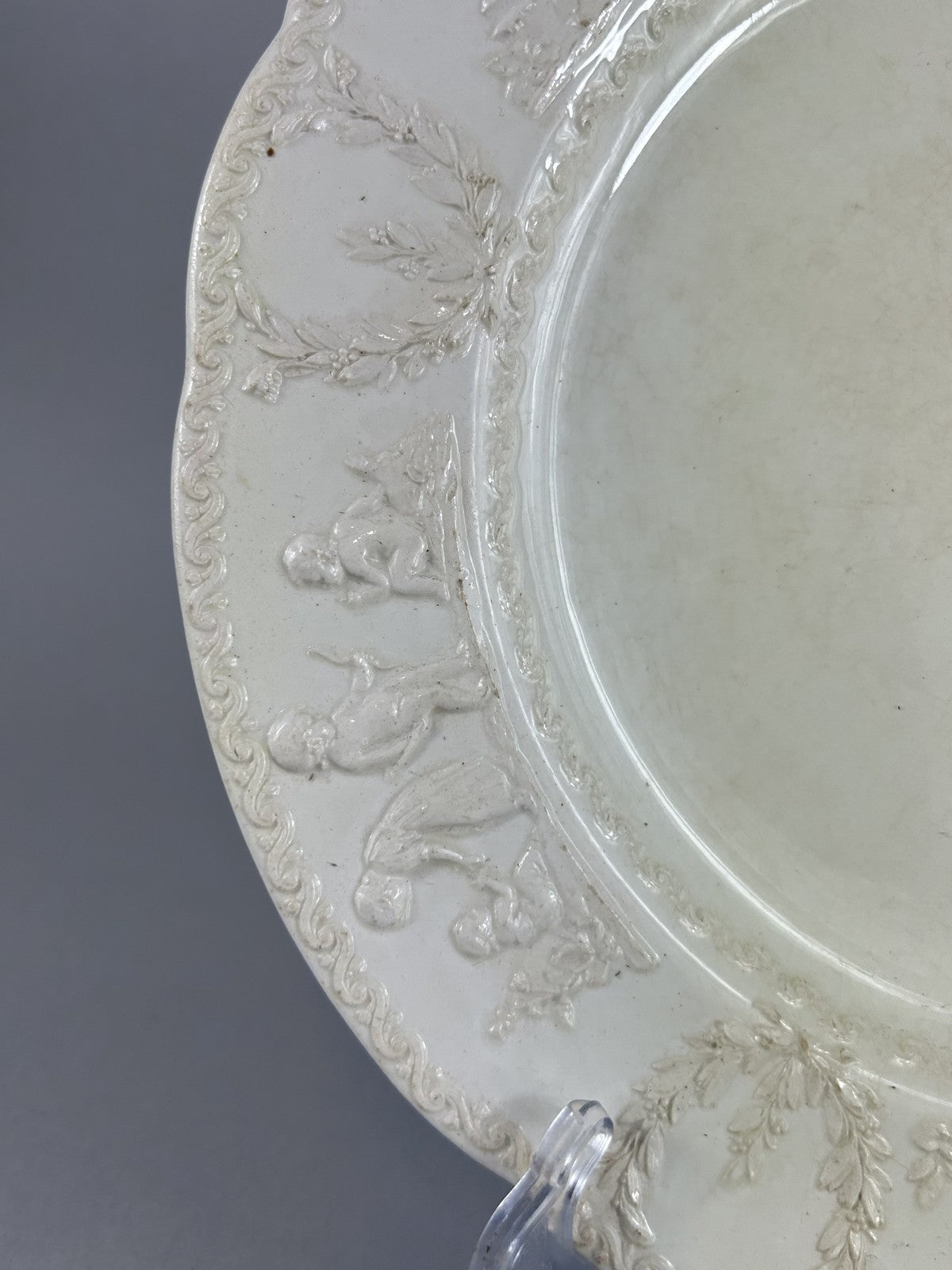 Early Wedgwood creamware plate with moulded putti border, 26cm
