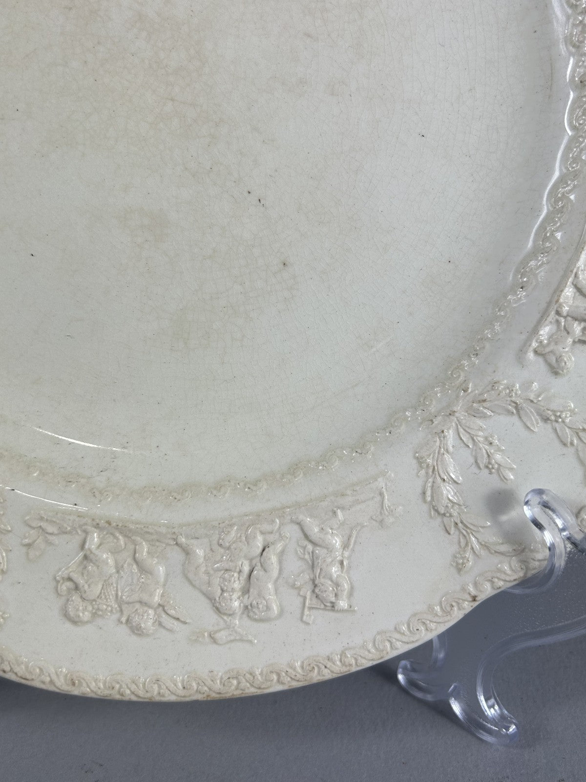 Early Wedgwood creamware plate with moulded putti border, 26cm