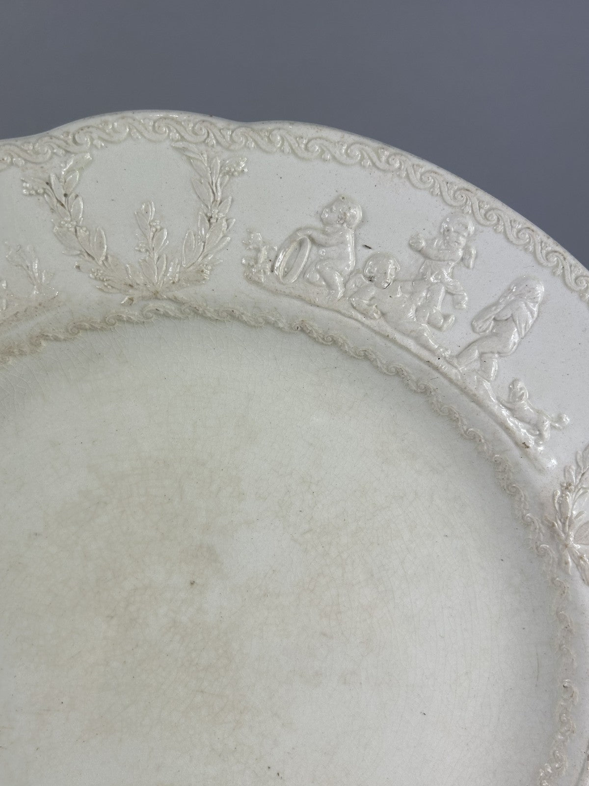 Early Wedgwood creamware plate with moulded putti border, 26cm